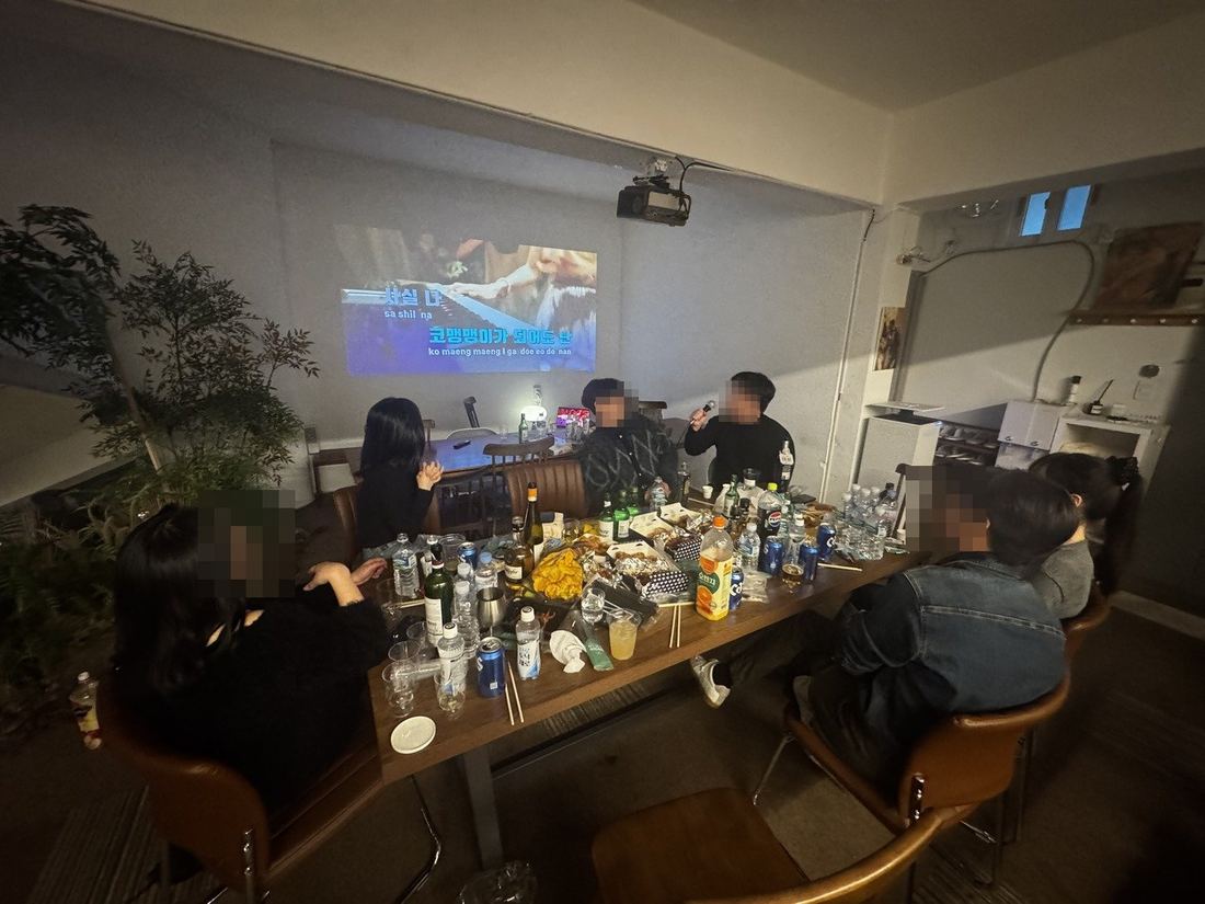 노래방 화면 앞 테이블에서 노래하는 사람들
