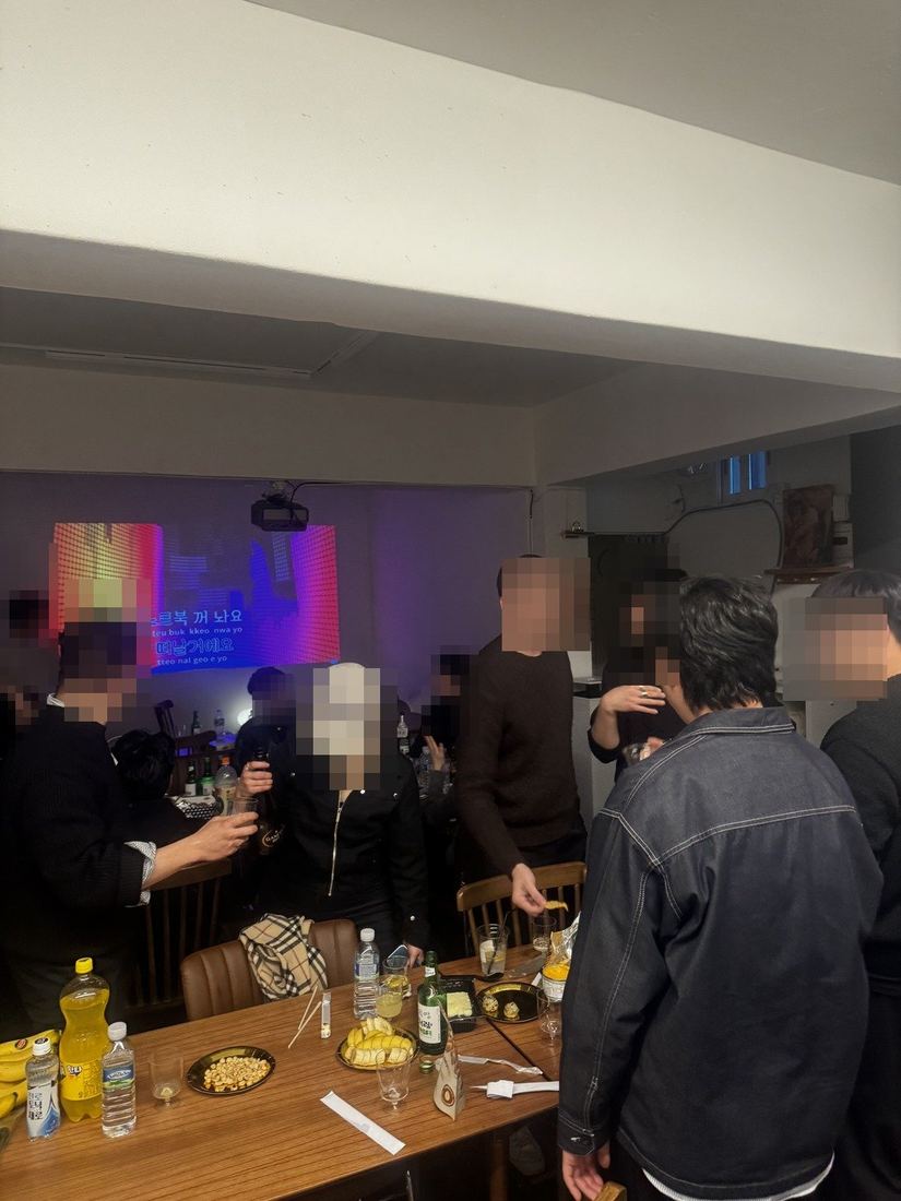 무지개 조명 아래 잔을 든 사람들